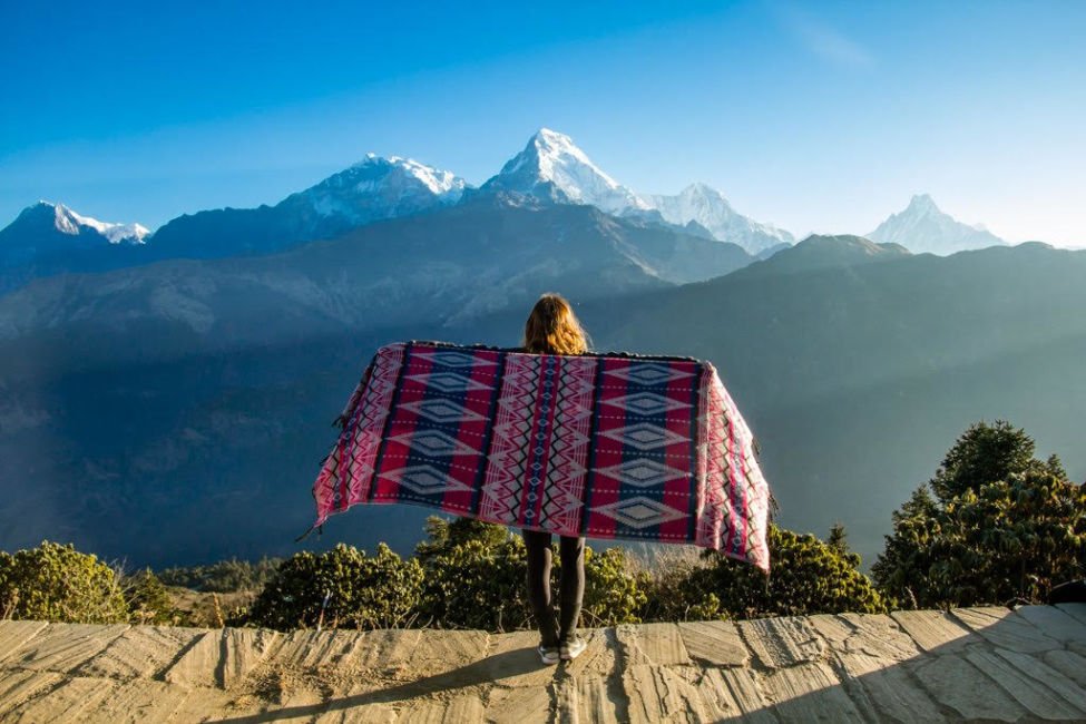 A woman holding a printed cloth doing sightseeing in the mountains