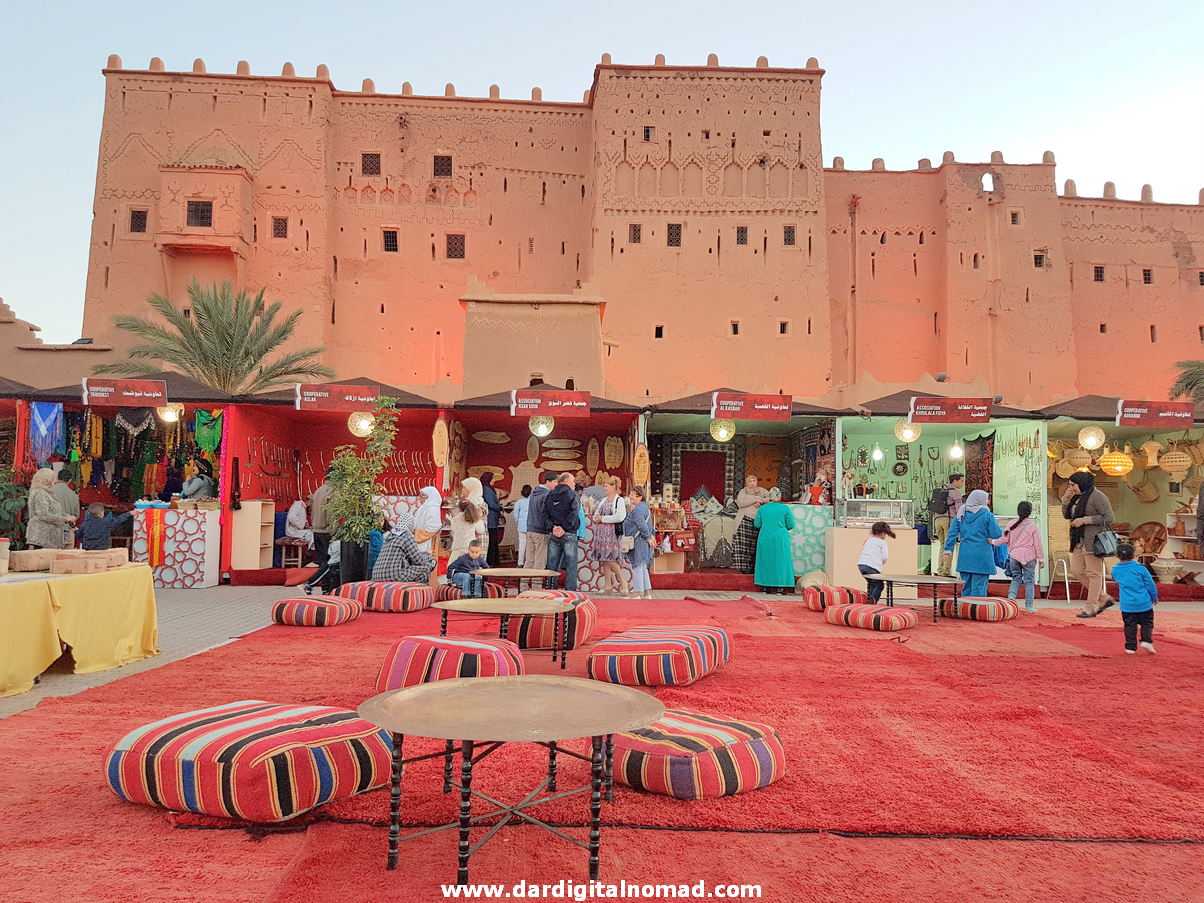 A red carpet with some tables, stores and tourists with a view of an architectural building 