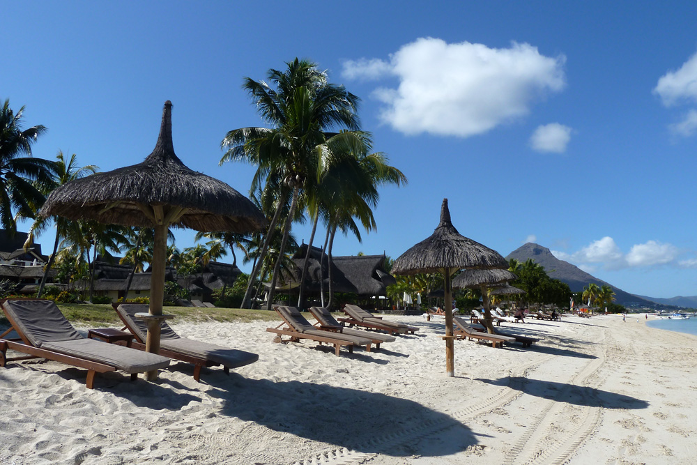 Coconut trees, wicker umbrella and some easy chairs on Paradis beach lounge mauritius