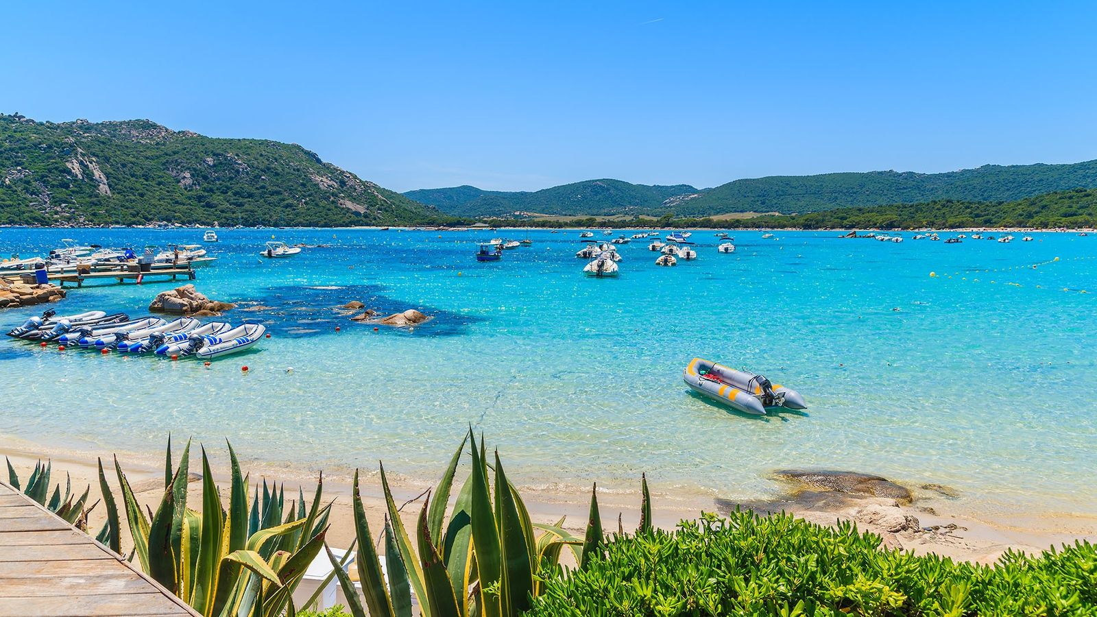 The Corsica beach with mini boats surrounded by mountains