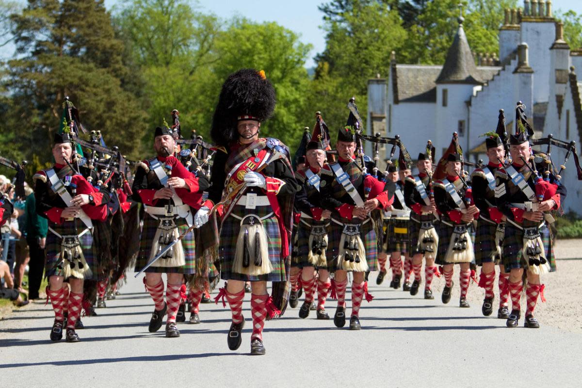 Scottish men on parade wearing their national kilt dresses and all playing bagpipes
