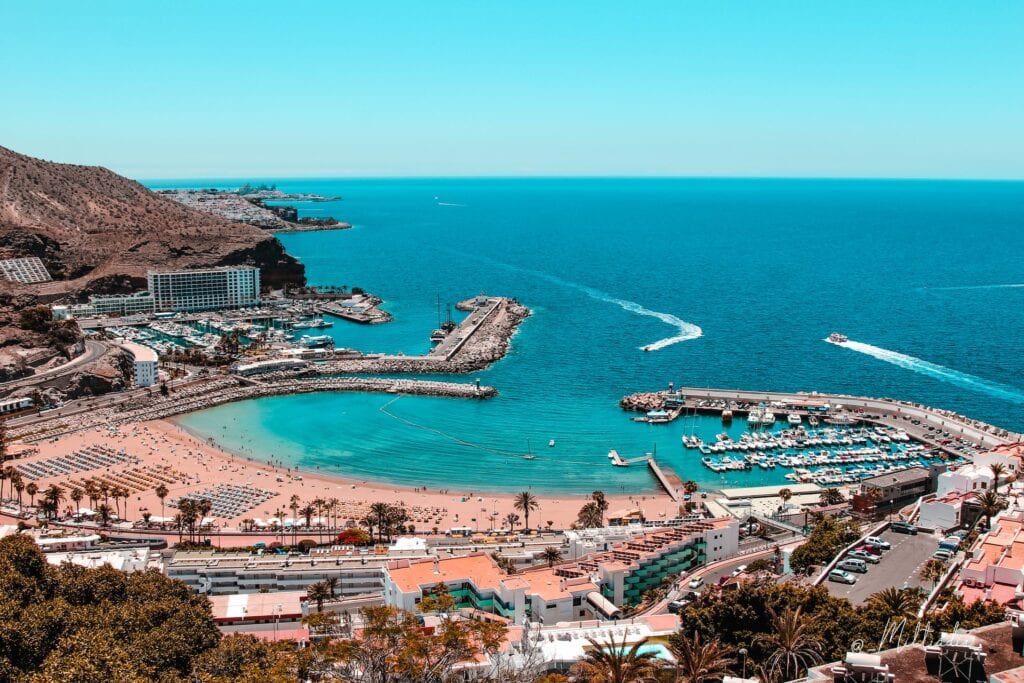 Gran Canaria beach with boats and resorts filled with tourists alongside