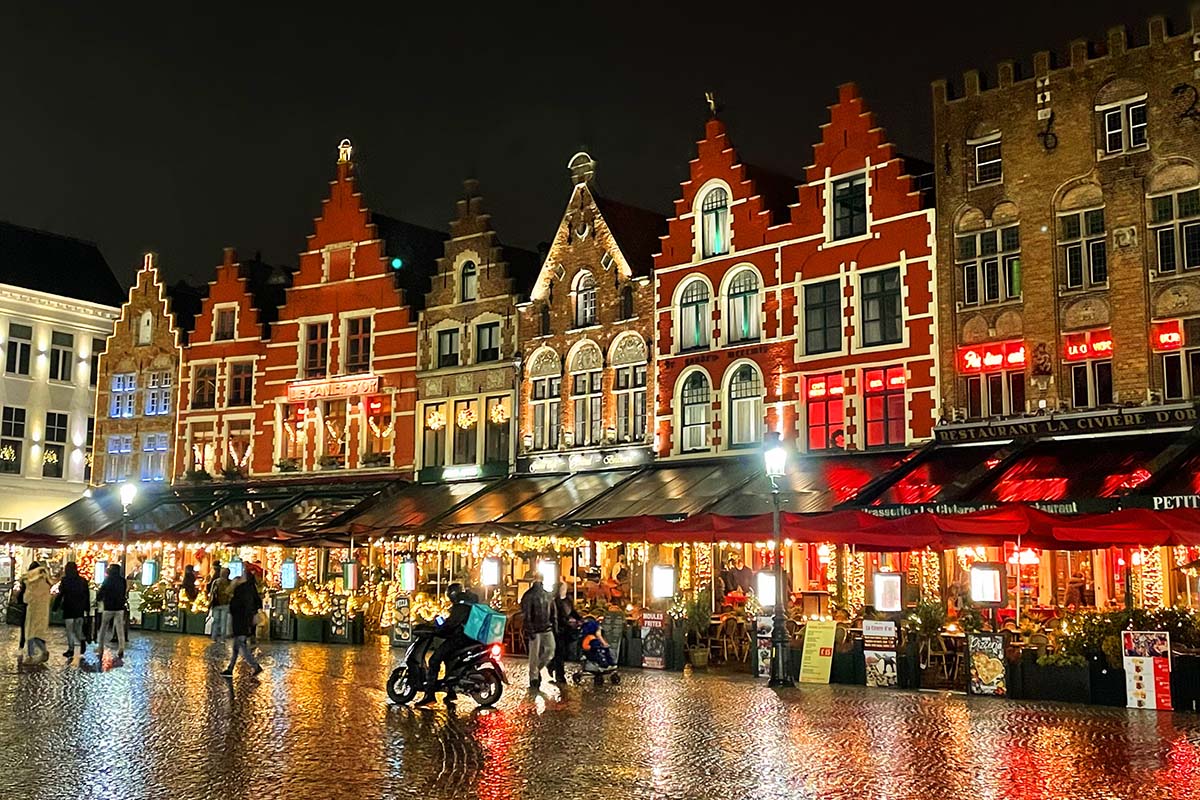 The night view shows red and gray buildings with lots of lighting and people shopping and walking on the streets.