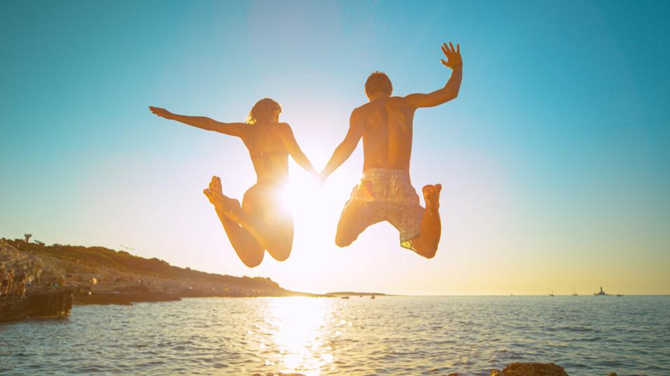 A man and woman jumping in the sea
