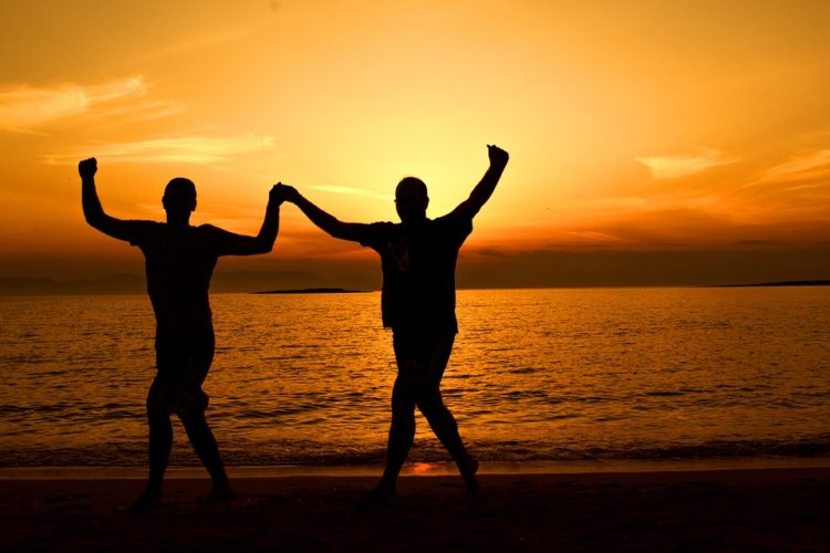 Two greek people dancing at sunset by the sea