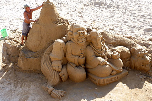 Cannes beach sand sculpture with a man working on it