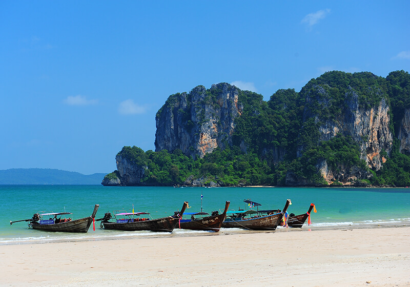 There are five boats that are drifting in the sea, as well as a large chunk of rock called limestone