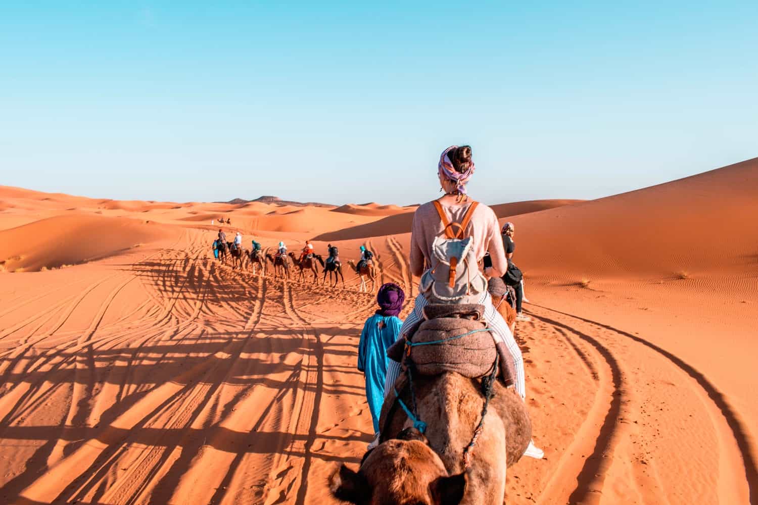 Some people walking and riding the camel at the dessert
