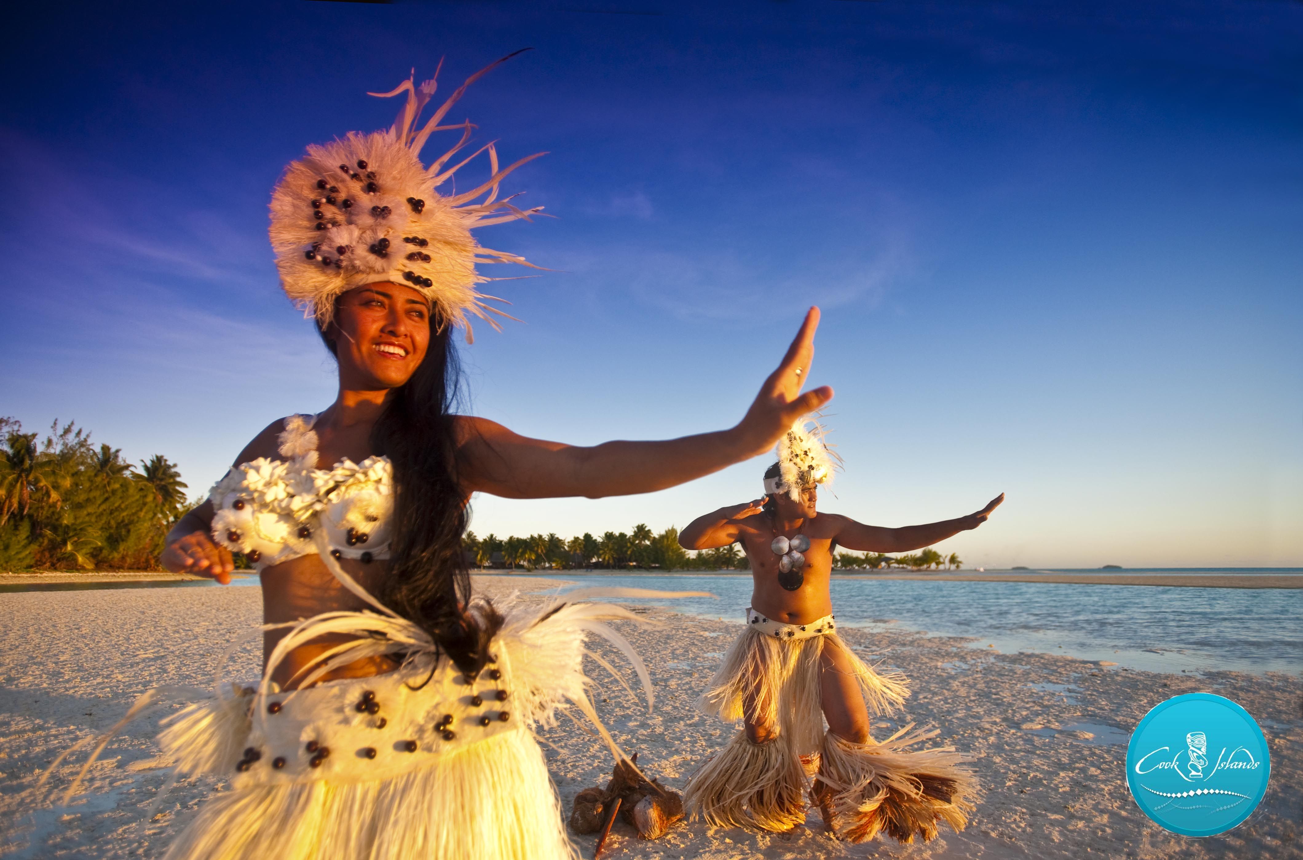 A cook islander man and woman dancing their traditional dance along the beach