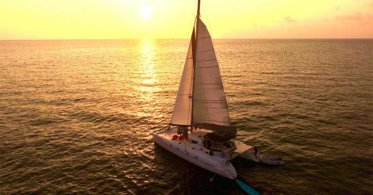 A Boat Sailing In The Sunrise
