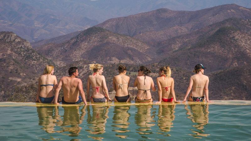 A group of young adults sitting beside an infinity pool