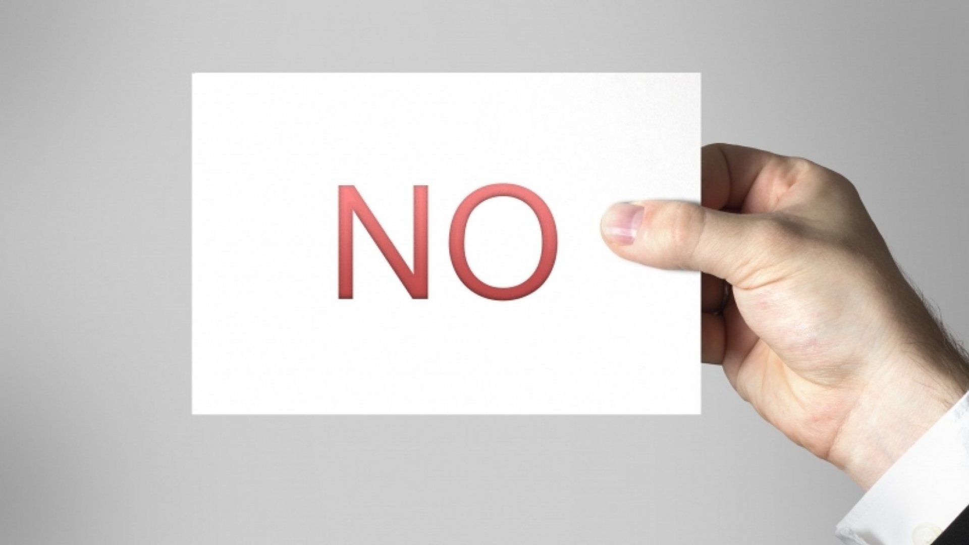 A man's hand holding a card with the word NO