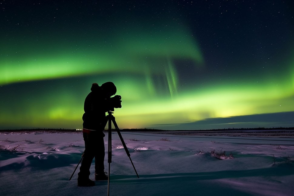 A man setting up his camera to capture the Northern Lights