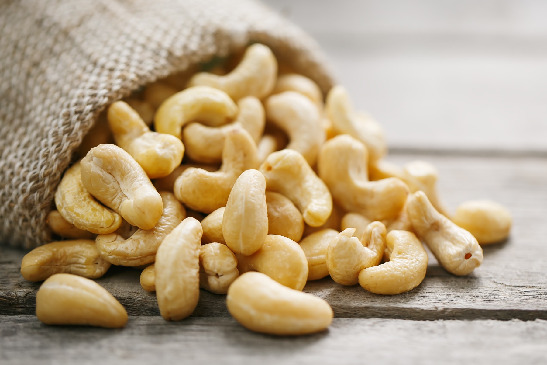 Peelled cashews pouring from a brown bag